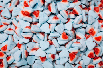 Background of blue and red gummy heart-shaped candies, top view.