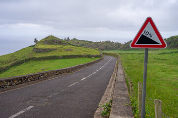 Asphalt road with road traffic sign indicating 10 slope on the Azorean island of Santa Maria, Portugal