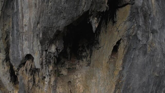 Drone hovers in front of a massive limestone wall in El Nido, Palawan, revealing a deep, natural cave high above the forest. The site is unreachable by foot, hidden in vertical karst rock.