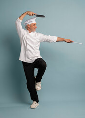 Portrait of a happy male chef cook holding knife isolated on a blue background