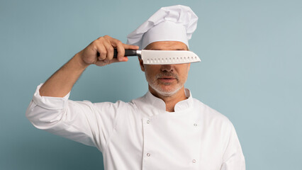 Portrait of a happy male chef cook holding knife isolated on a blue background