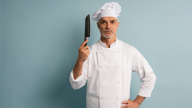 Portrait of a happy male chef cook holding knife isolated on a blue background