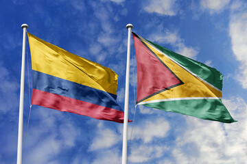 Colombia and Guyana flags proudly waving side by side against a brilliant blue sky, symbolizing...