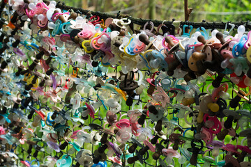Colorful baby pacifiers on the fence. The place where babies refuse to use pacifiers anymore