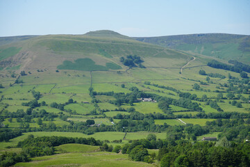 Obraz premium Scenic countryside landscape showcasing rolling hills, pastureland, stone walls, farmhouses, and woodland in the UK.