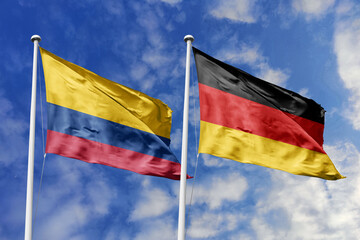 Colombia and Germany flags proudly waving side by side against a brilliant blue sky, symbolizing strong international ties, cultural exchange, and global cooperation.