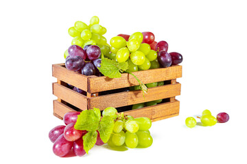 Bunches of green and red juicy grapes with leaves in a wooden box.
