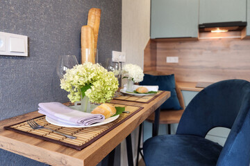 Breakfast table set with fresh flowers and baked bread in cozy kitchen area during morning hours