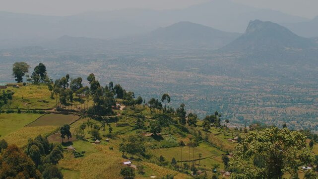 Panorama of hazy mountain peaks and the Great Rift valley with scattered on it buildings.