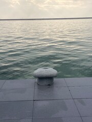 Concrete Pier with Mooring Bollard on Calm Water – Minimalist Waterside Scene Evoking Stillness,...