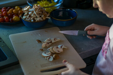 Cropped image of cute little girl cooking in kitchen at home. High quality photo