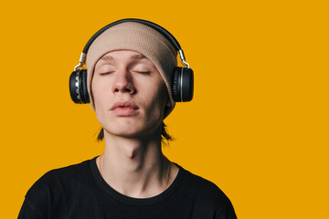 A Young Man Truly Enjoying Listening to Music while Wearing Headphones Against a Bright Background