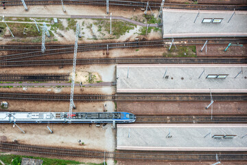 Top-down aerial view of railway platforms and single train arriving station, symmetrical layout...