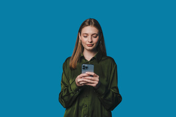 A young woman cheerfully using her smartphone against a vibrant blue background