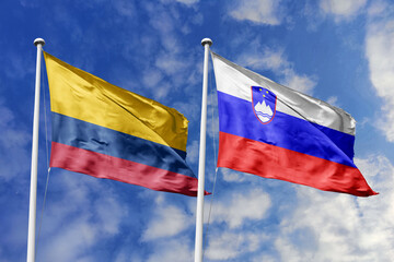 Waving flags of Colombia and Slovenia against a vibrant blue sky, symbolizing international...