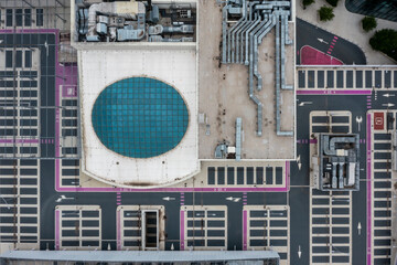 Top-down view of modern building rooftop with ventilation systems and blue circular skylight,...