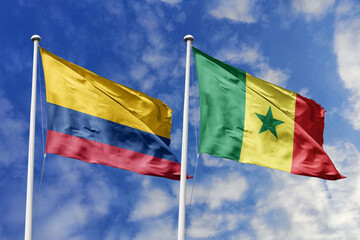 Waving flags of Colombia and Senegal against a vibrant blue sky, symbolizing international...