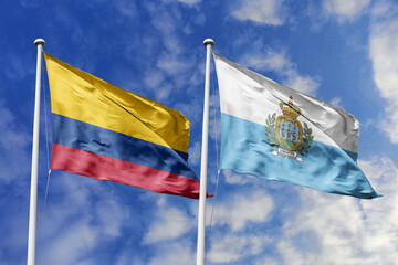 Waving flags of Colombia and San Marino against a vibrant blue sky, symbolizing international...