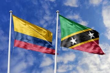 Waving flags of Colombia and Saint Kitts and Nevis against a vibrant blue sky, symbolizing...