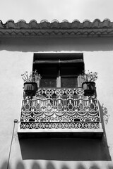Wrought iron balcony with potted plants and wooden blind in Villanueva de los Infantes town