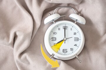 Alarm clock on bed, top view. Fall back concept
