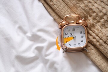 Alarm clock on bed, top view. Fall back concept