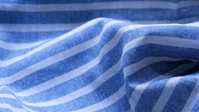 Fabric texture background of soft blue stripes pattern. Close-up cloth texture. Concept of bold lines, wrinkled, cozy, cotton, stylish, minimal, fashion, textiles for backdrop, wallpaper, print, web.