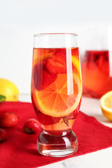 Glass and jug of infused water with strawberry and lemon on white background