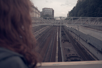 teenager girl looking on railway tracks background, cinematic. A scenic view of an old railway Moscow Russia 06.24.2025