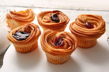 Board of tasty cruffins with jam and chocolate on white wooden background