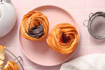 Plate of tasty cruffins with chocolate and jam on pink tile background