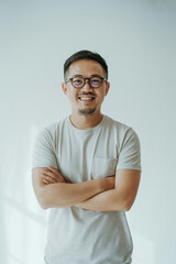 Fototapeta premium Portrait of a smiling asian man with glasses and arms crossed