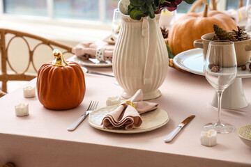 Autumn table setting decorated for Thanksgiving Day with cutlery, folded napkin and pumpkin, closeup
