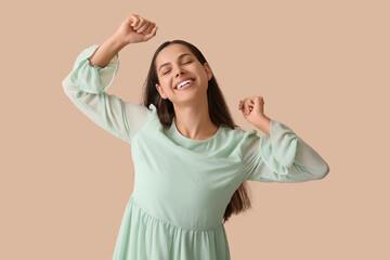 Cheerful young woman on beige background