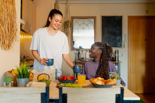 Two women enjoying a healthy breakfast together at their kitchen table, sharing a moment of connection and conversation - Powered by Adobe