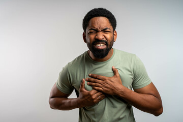 Heart attack symptoms and chest pain in African man, suffering with painful expression, young adult...