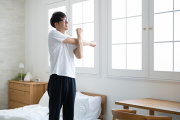 部屋で伸びをする男性