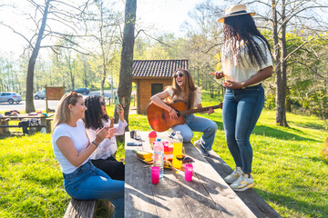 Friends enjoying music and dancing at a picnic in the park
