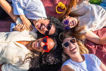 Four young women lying on blanket smiling and having fun