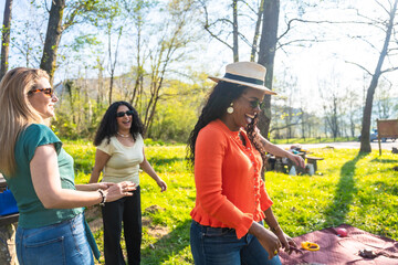 Three happy multi ethnic women playing outdoor games in a park during a sunny day