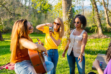 Young women playing music and taking pictures in a park