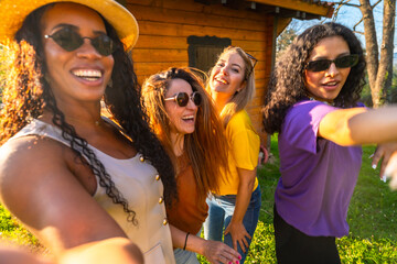 Four cheerful women taking a selfie outdoors in a garden