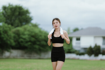 A fit and focused woman jogs outdoors in a serene green park, wearing activewear and earphones,...