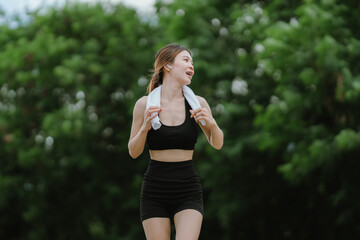 A fit and focused woman jogs outdoors in a serene green park, wearing activewear and earphones,...
