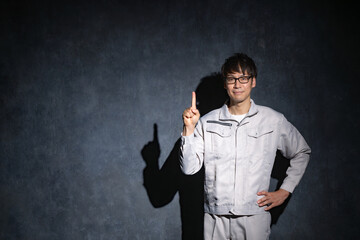 指差しする作業服の男性