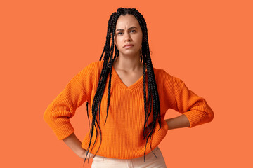 Beautiful young thoughtful African-American woman on orange background
