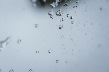 Raindrops and bubbles scatter across a wet surface, capturing nature’s freshness and moisture in...
