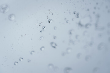 Raindrops and bubbles scatter across a wet surface, capturing nature’s freshness and moisture in...