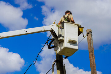 Worker is in lift, conducting repairs on power lines while ensuring safety efficiency after hurricane