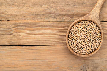 Dry mustard seeds are displayed in a wooden spoon on a textured wooden background table top.